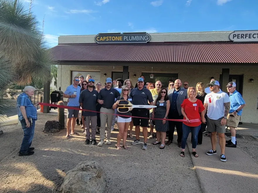 Ribbon-cutting ceremony outside the Capstone Plumbing shop on E Cave Creek Rd, with the team and Cave Creek community members